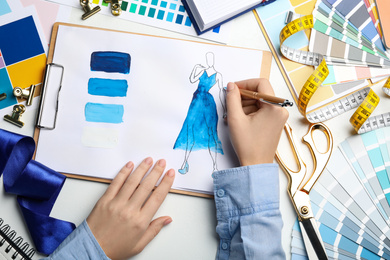Fashion designer drawing dress at table, top view