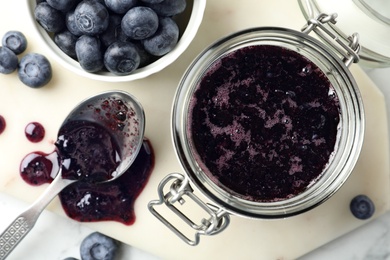 Jar of blueberry jam and fresh berries on table, top view