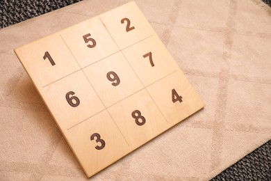 Wooden board with numbers on beige rug indoors. Montessori toy