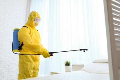 Employee in protective suit sanitizing doctor's office. Medical disinfection
