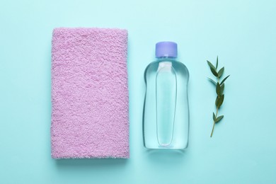 Bottle of baby oil, towel and leaves on turquoise background, flat lay