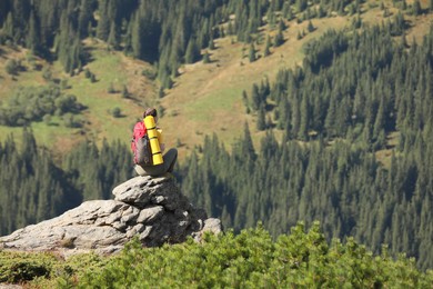 Tourist with backpack enjoying mountain landscape on rocky peak, back view