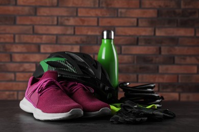 Different cycling accessories on black table against brick wall