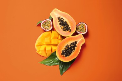 Fresh ripe papaya and other fruits on orange background, flat lay
