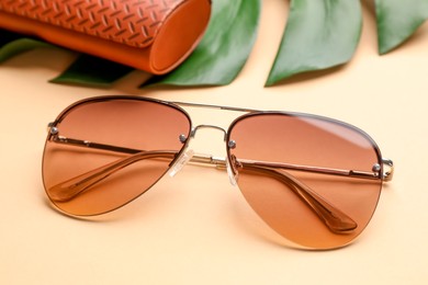 Stylish elegant sunglasses on beige background, closeup
