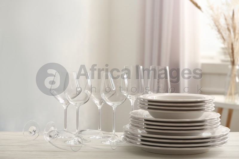 Photo of Set of clean dishware and wineglasses on white table indoors