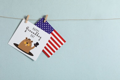 Happy Groundhog Day greeting card and American flag hanging against light background, space for text