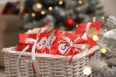 Photo of Basket full of gifts in paper bags for Christmas advent calendar on blurred background, closeup