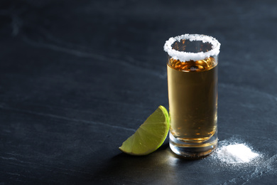 Mexican Tequila shot, lime slice and salt on grey table. Space for text