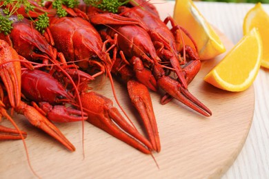 Delicious red boiled crayfish and orange on wooden board, closeup