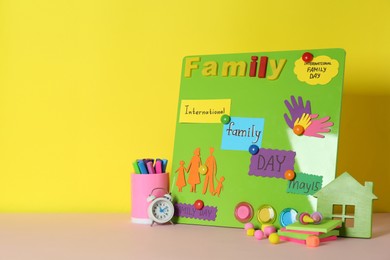 Happy International Family Day. Composition with stationery on pink table against yellow background, space for text