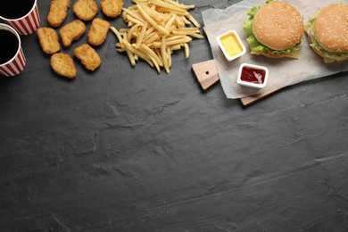 Flat lay composition with delicious fast food menu on black table. Space for text