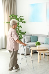 Elderly woman using walking frame at home
