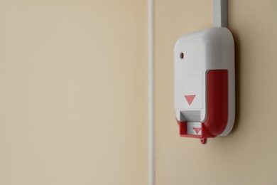 Photo of Fire alarm switch on light wall indoors. Space for text