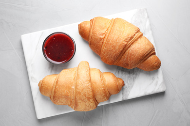 Photo of Tasty fresh croissants and jam on grey table, top view
