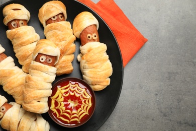Spooky sausage mummies for Halloween party served on grey table, top view. Space for text