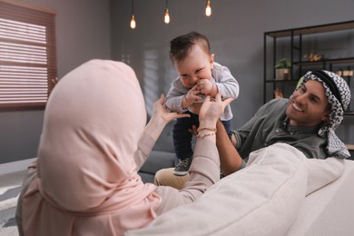 Happy Muslim family with little son in living room