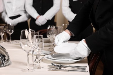 Photo of Man wearing formal suit teaching trainees in restaurant, closeup. Professional butler courses
