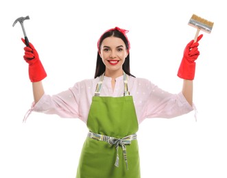 Young housewife with hammer and brush on white background