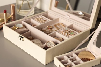 Elegant jewelry boxes with expensive wristwatches and beautiful bijouterie on grey table