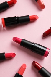 Photo of Many bright lipsticks on pink background, flat lay