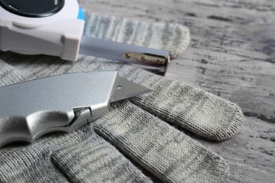 Photo of Utility knife,measuring tape and glove on rustic table, closeup