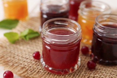 Jars of different jams on table, closeup