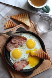 Tasty fried eggs with bacon and toasts served on table, flat lay