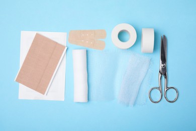 White bandage and medical supplies on light blue background, top view