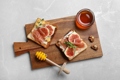 Photo of Delicious sandwiches with figs, proscuitto and cheese on light table, top view
