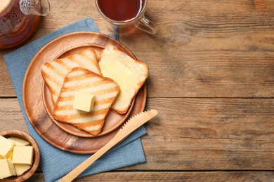 Photo of Tasty toasts with butter served on wooden table, flat lay. Space for text