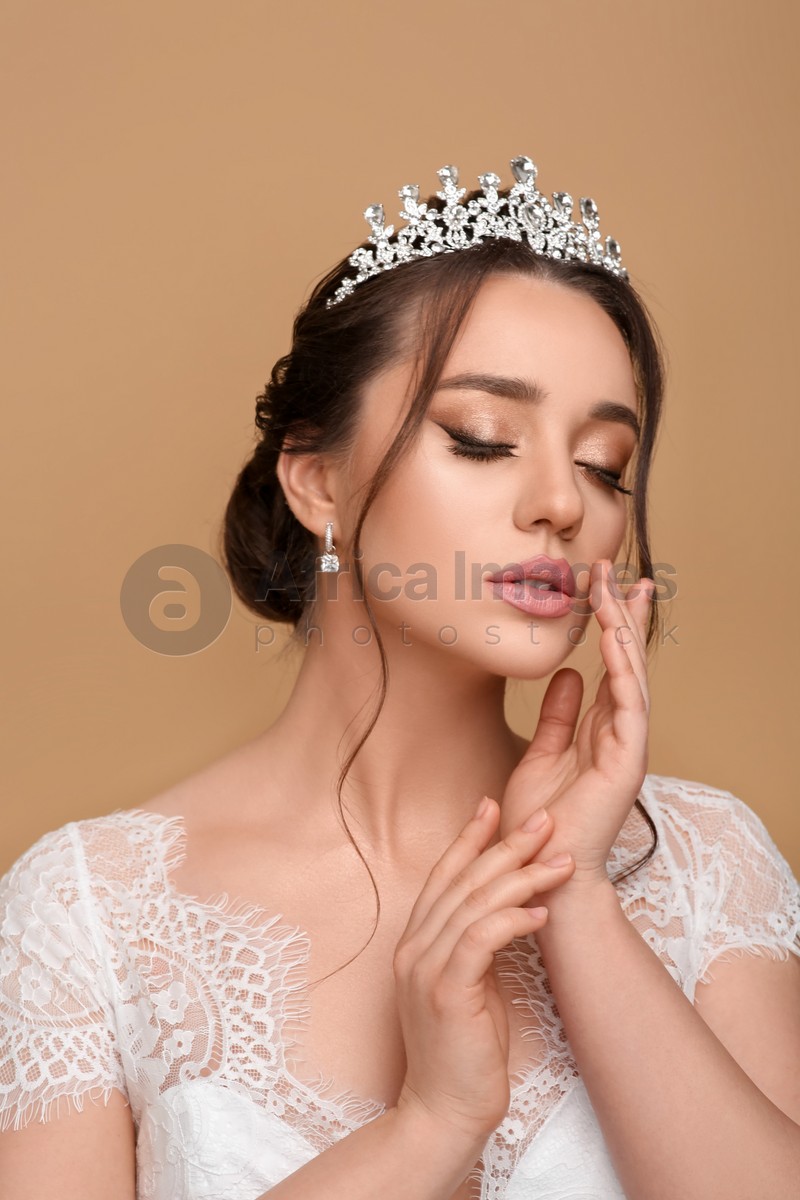 Photo of Beautiful young woman wearing luxurious tiara on beige background