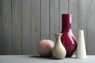 Stylish ceramic vases on grey wooden table. Space for text