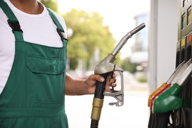 Worker taking fuel pump nozzle at modern gas station, closeup