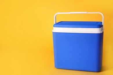 Closed blue plastic cool box on orange background. Space for text
