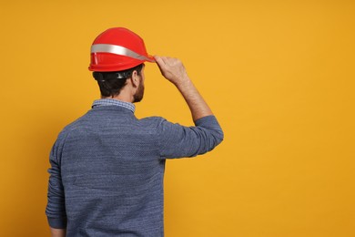 Professional engineer in hard hat on yellow background, back view. Space for text