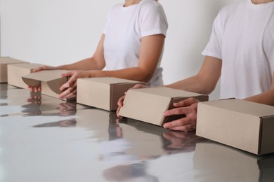 Workers folding cardboard boxes at table, closeup. Production line 