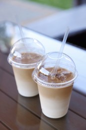 Plastic takeaway cups of delicious iced coffee on table in outdoor cafe
