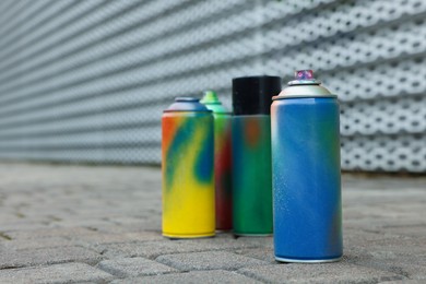 Photo of Used cans of spray paints on pavement, closeup. Space for text