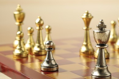 Chessboard with game pieces on beige background, closeup