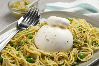 Photo of Delicious spaghetti with burrata cheese, peas and pesto sauce on plate, closeup