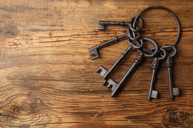 Bunch of steel keys on wooden background, top view with space for text. Safety concept