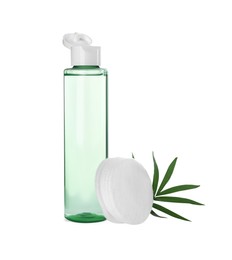 Bottle of micellar cleansing water, cotton pads and green twig on white background