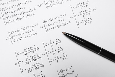 Sheet of paper with mathematical formulas and pen, top view