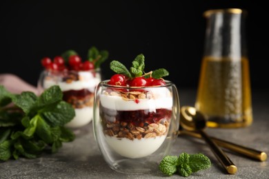 Delicious yogurt parfait with fresh red currants and mint on grey table