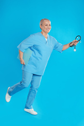 Mature doctor in uniform running on blue background