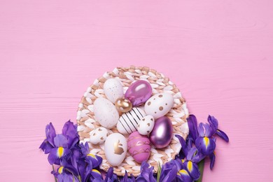 Photo of Flat lay composition with festively decorated Easter eggs and iris flowers on pink wooden background