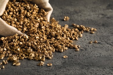 Overturned sack of gold nuggets on grey table