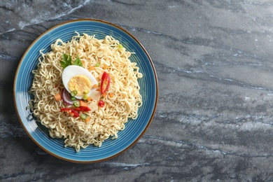 Photo of Plate of tasty noodles with egg and vegetables on marble background, top view. Space for text