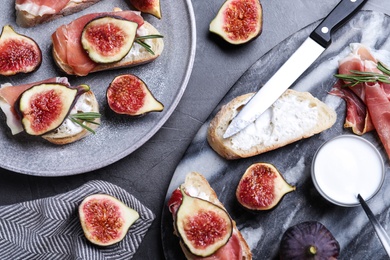 Sandwiches with ripe figs, cream cheese and prosciutto served on black table, flat lay